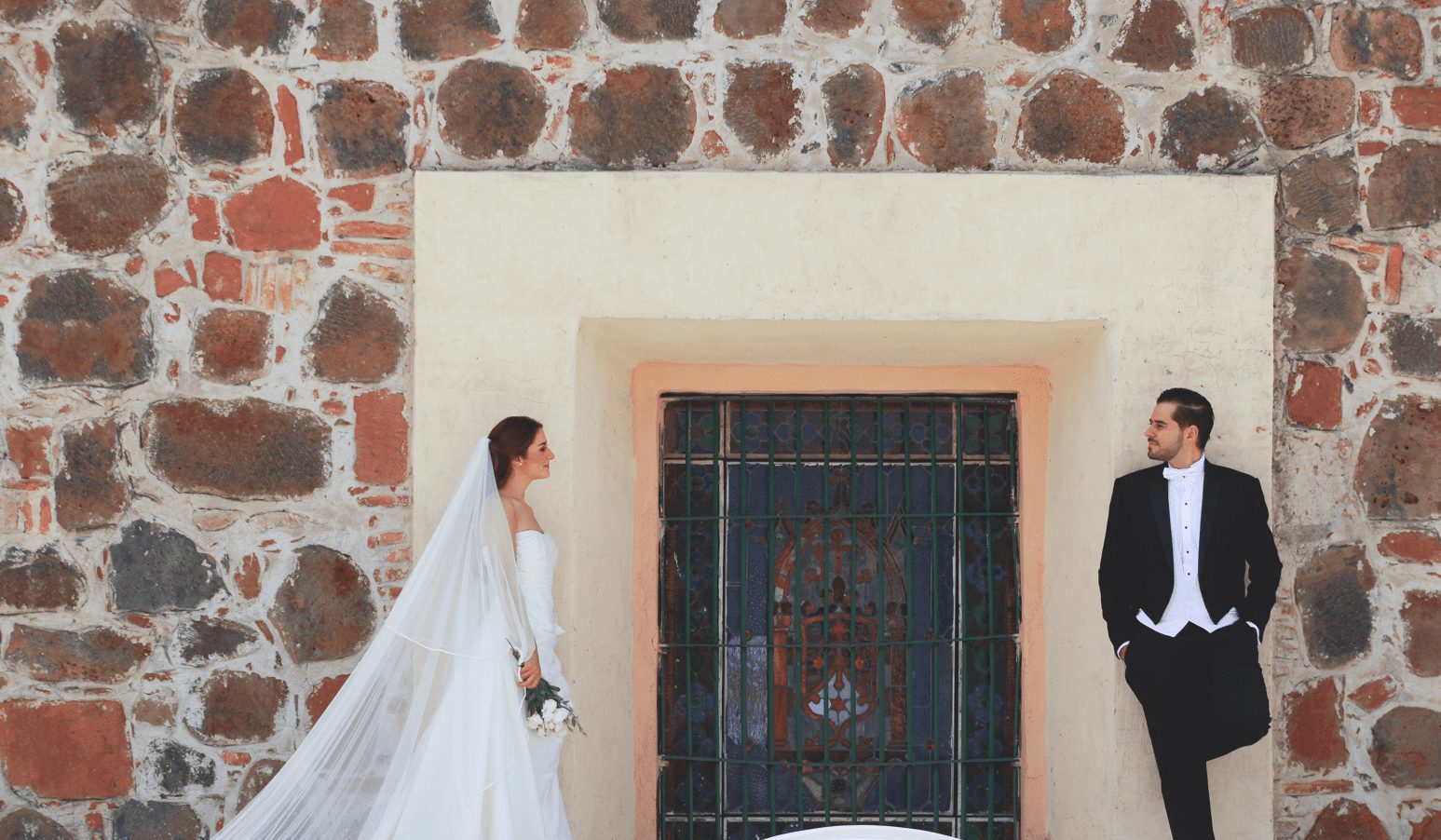Novios frente al muro de piedra y vitral del Ex Convento de Santa Teresa