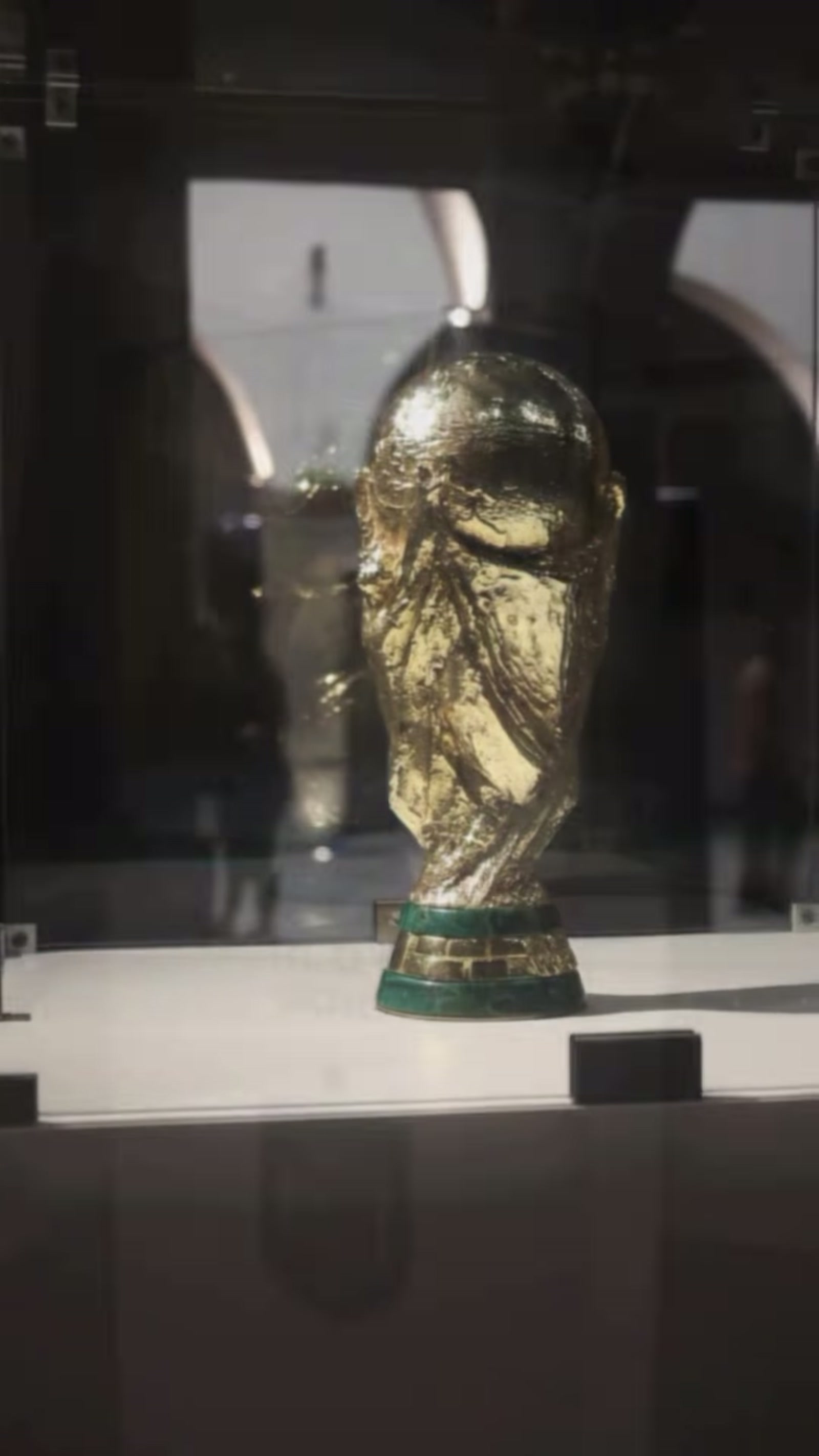 Trofeo de la Copa Mundial FIFA en vitrina de cristal, con los arcos del Ex Convento reflejados