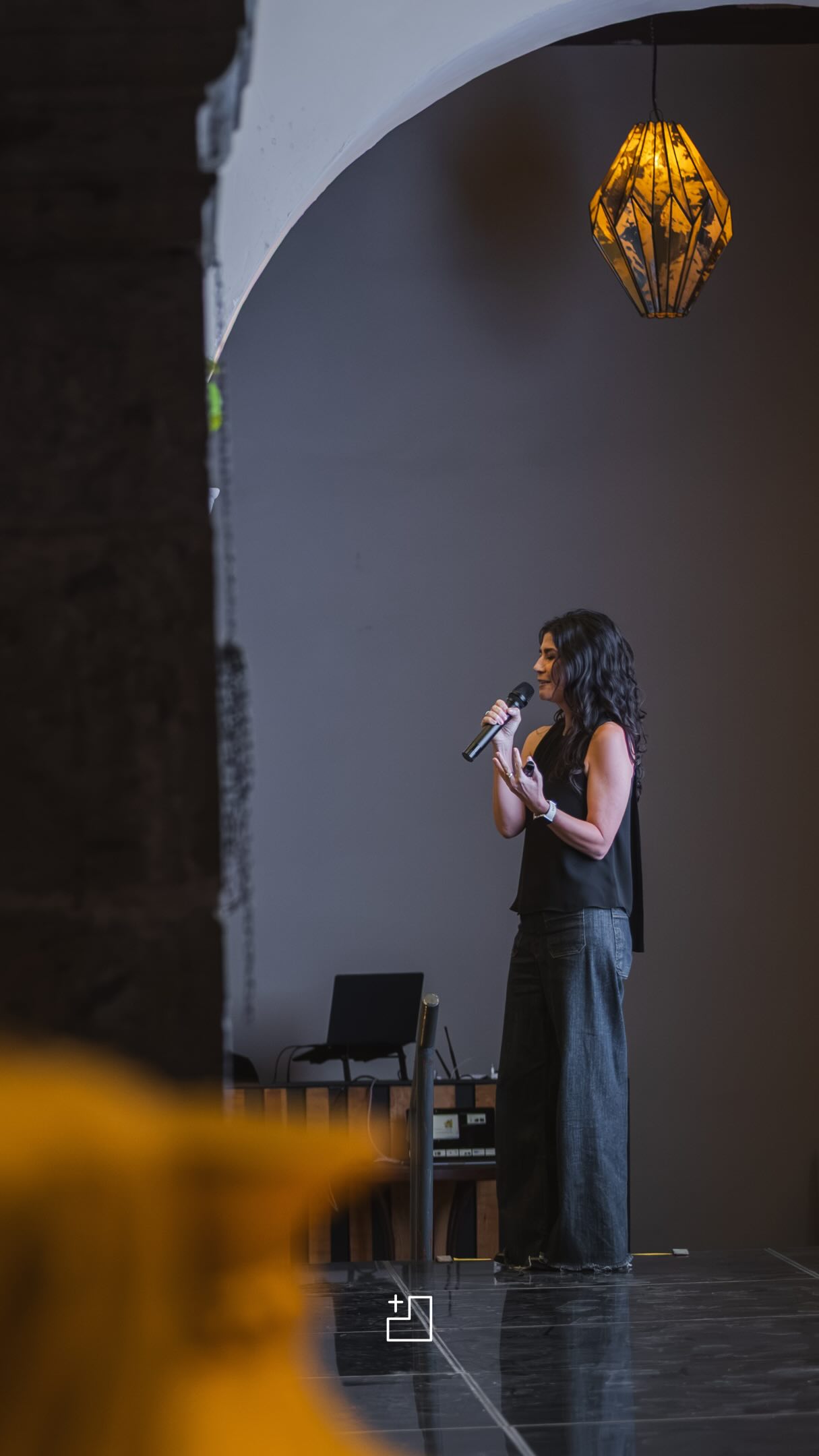 Ponente con micrófono presentando bajo un arco del Ex Convento durante un evento empresarial